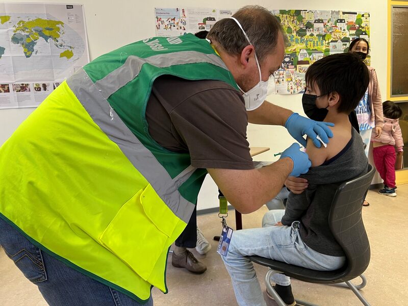 Notfallsanitäter Marc Pudenz vom mobilen Impfteam des Landkreises Kassel impft den 11-jährigen Ali aus Afghanistan.