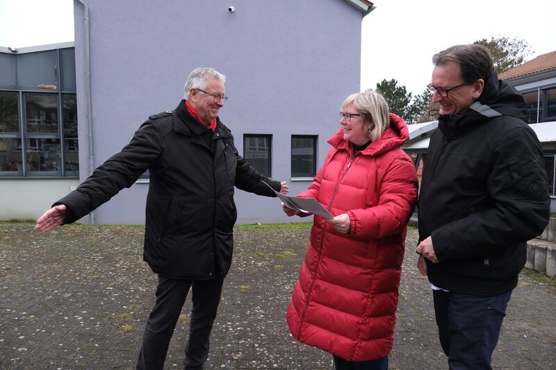 Schulleiter Ludger Brinkmann informiert Vizelandrätin Silke Engler und Lehrer Martin Götze, wo das Fliegende Künstlerzimmer auf dem Schulhof landen wird. (v.l.)