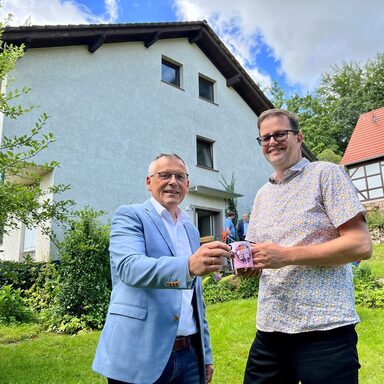 Symbolischer Akt: Landrat Andreas Siebert und Wesertals Bürgermeister Cornelius Turrey tauschen den Schlüssel für das Haus am Mühlenplatz 7 gegen eine Wesertal-ist-Bunt-Kaffeetasse.